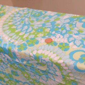 May include: A close-up of a fabric with a swirling pattern in shades of blue, green, and white. The fabric has a paisley-like design.