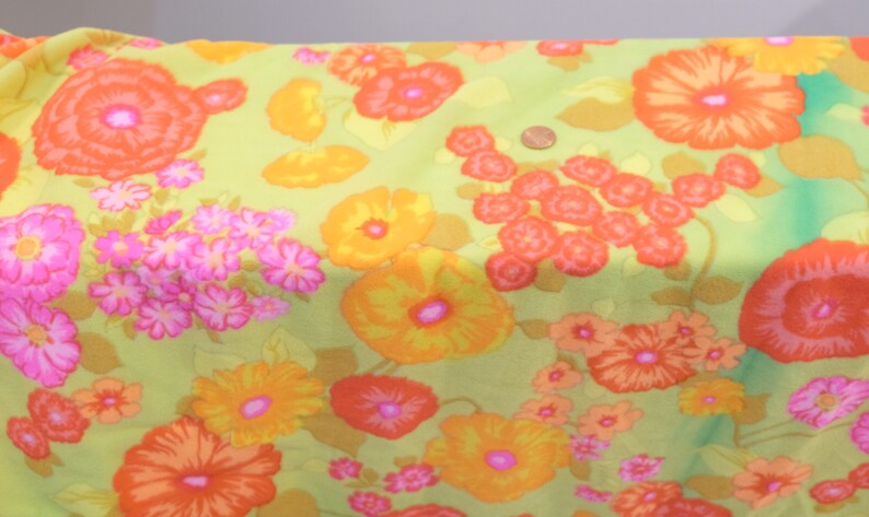 Puede incluir: Una tela verde con un patr&oacute;n floral con flores naranjas, amarillas y rosas. La tela tiene un aspecto vintage y ser&iacute;a ideal para proyectos de manualidades.