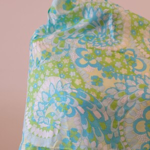 May include: A blue and green paisley patterned fabric with white accents. The fabric is draped over a surface.