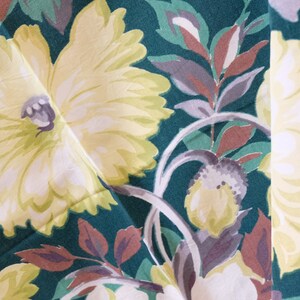 K&ouml;nnte beinhalten: Nahaufnahme eines Stoffes mit Blumenmuster. Der Stoff ist gr&uuml;n mit gelben, wei&szlig;en und braunen Blumen. Die Blumen sind stilisiert und haben einen Vintage-Look.