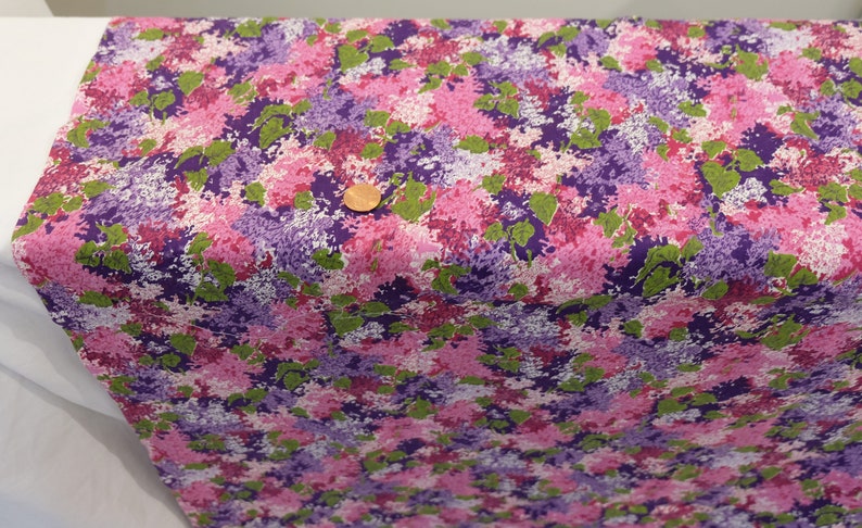 May include: Purple, pink and green floral fabric with a white background. The fabric has a small-scale print of flowers and leaves.