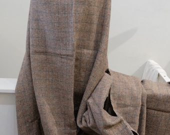 May include: A brown and beige checkered fabric with a fine weave. The fabric is folded and draped over a white surface.