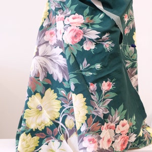 K&ouml;nnte beinhalten: Ein gr&uuml;ner Stoff mit einem Blumendruck mit rosa, wei&szlig;en und gelben Blumen. Der Stoff hat einen Vintage-Charakter und w&auml;re perfekt f&uuml;r Bastel- oder N&auml;hprojekte.