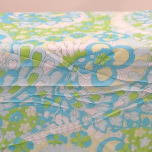 May include: A blue and green fabric with a floral pattern. The fabric has a light blue background with green and white flowers.