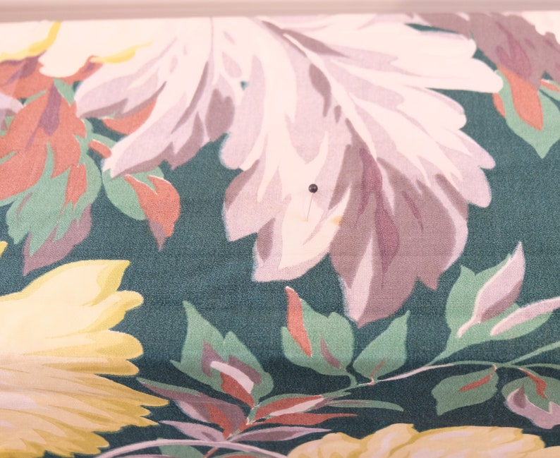 K&ouml;nnte beinhalten: Eine Nahaufnahme eines Stoffes mit einem Blumenmuster. Der Stoff ist dunkelgr&uuml;n mit rosa, wei&szlig;en und gelben Blumen. Die Blumen sind stilisiert und haben einen Vintage-Look.