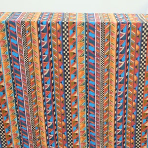 May include: A colorful fabric with a repeating geometric pattern of stripes and triangles in shades of orange, blue, red, and brown.