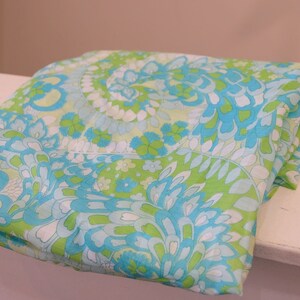 May include: A folded fabric with a green, blue, and white paisley pattern.