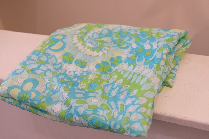 May include: A folded fabric with a green, blue, and white paisley pattern.