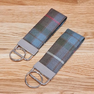 May include: Two keychains with silver key rings. The keychains are made of a blue, green, and red plaid fabric.