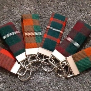 Puede incluir: Seis llaveros coloridos con patrones de cuadros en tonos de verde, naranja, rojo y blanco. Cada llavero tiene un anillo de llave plateado.