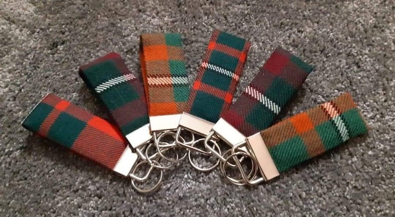 Puede incluir: Seis llaveros coloridos con patrones de cuadros en tonos de verde, naranja, rojo y blanco. Cada llavero tiene un anillo de llave plateado.