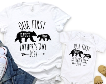 May include: White t-shirt and bodysuit with black bear silhouettes and the text "Our First Father's Day 2024". The larger bear has the word "Daddy" written on it and the smaller bear has the word "Emma" written on it.