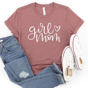 May include: A mauve t-shirt with the text "girl mom" in white script with a small white heart.