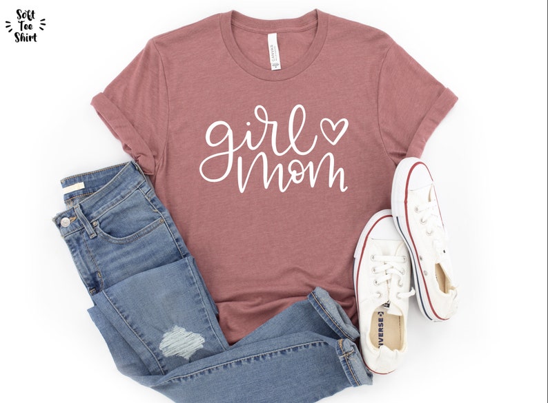 May include: A mauve t-shirt with the text "girl mom" in white script with a small white heart.