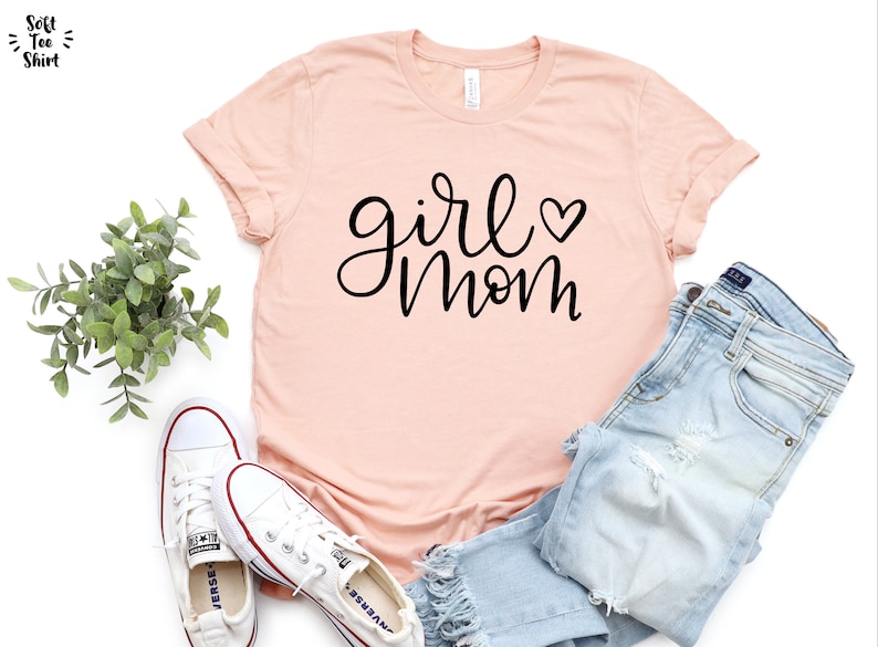 May include: A light pink t-shirt with the text "girl mom" in black script with a small heart symbol.
