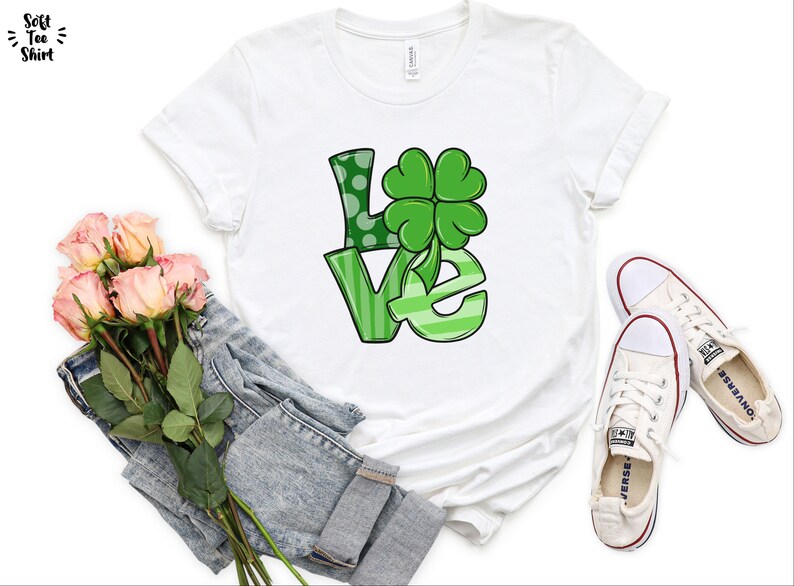 May include: White t-shirt with a green "LOVE" graphic featuring a four-leaf clover.