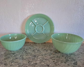 May include: Two light green glass bowls with a subtle swirl pattern on the exterior and one matching light green glass divided plate with a central circular section and four radiating compartments for serving food items.