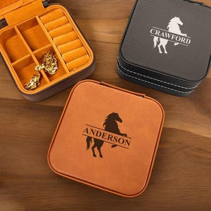 May include: Two brown and black square jewelry boxes with a horse silhouette and personalized names. The box on the left says "Anderson" and the box on the right says "Crawford".