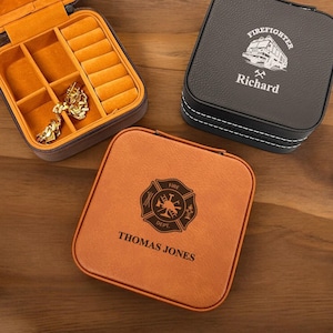 May include: Two brown leatherette jewelry boxes with personalized engravings. One box features a firefighter emblem with the name "Thomas Jones". The other box features a fire truck with the name "Richard".