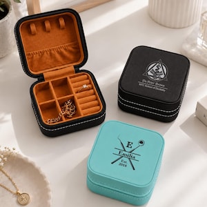 May include: Two square jewelry boxes, one black and one light blue, featuring dental-themed engravings. The black box displays Dr. Peter Brown NYC School of Dentistry, while the blue box shows Emilia Est. 2018. An open black box reveals orange lining.