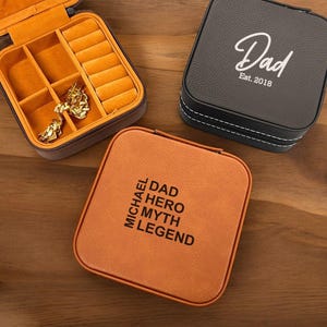 May include: Two brown leather jewelry boxes with different engravings. One box says "Dad Est. 2018" and the other says "Michael Dad Hero Myth Legend".