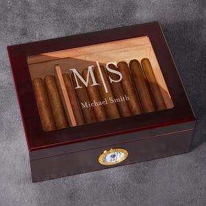 May include: A mahogany wood cigar box with a glass top and a hygrometer. The box is personalized with the initials "M|S" and the name "Michael Smith".