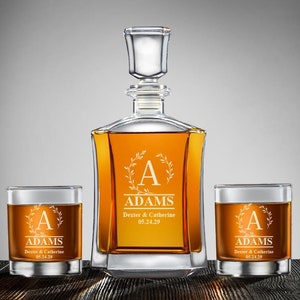 May include: A personalized decanter set with two glasses. The decanter and glasses are engraved with the letter "A", the name "ADAMS", and the date "05.24.29".