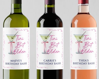 Könnte beinhalten: Drei Weinflaschen mit personalisierten Etiketten, auf denen "Tini Bit Older" mit einer Martini-Glasgrafik und einem rosa Band steht. Die Etiketten enthalten auch die Namen "Maeve's", "Carrie's" und "Thea's", gefolgt von "Birthday Bash".
