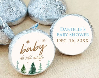 May include: Winter-themed baby shower favor tags with a white background, brown text, and a green watercolor forest design. One tag says "baby it's cold outside" and the other says "Danielle's Baby Shower Dec. 16, 20XX".