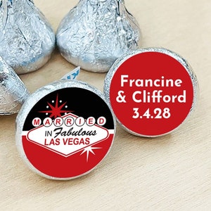 May include: Red and black round favor stickers with white text. One sticker says "Married in Fabulous Las Vegas" with a stylized casino sign. The other sticker says "Francine & Clifford 3.4.28".