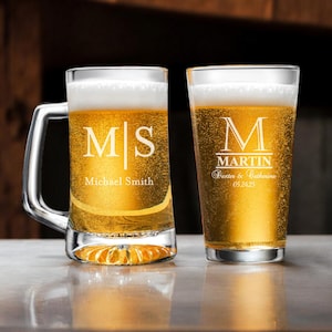 May include: Two personalized beer glasses. The first glass is a clear mug with a handle and the text "M|S Michael Smith" etched on the side. The second glass is a clear pint glass with the text "M MARTIN Dexter & Catherine 05.24.25" etched on the side.