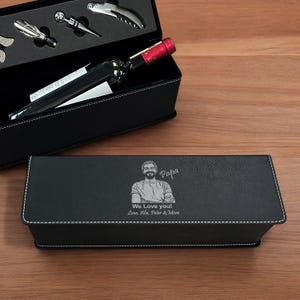 May include: A black wine gift set with a bottle of wine and wine tools. The set includes a black box with a personalized message and a picture of a man with the text "Papa" and "We Love You! Love, Alia, Peter & Mom."
