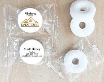 May include: Two clear plastic bags containing white round mints with printed text. One bag has a mint with the text "Welcome to our Open House" and the other bag has a mint with the text "Mark Bailey, Realtor, 918-210-8888, MarkBailey@email.com".