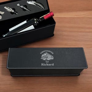 May include: Black leatherette wine box with a personalized inscription that reads "Firefighter Richard" and a silver engraved image of a fire truck. The box includes a bottle of wine and a set of wine accessories.