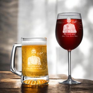 May include: Two personalized glasses, one filled with beer and the other with red wine. The beer mug has a handle and features an etched image and the words "Papa" and "We Love You! Love, Rita, Peter & Mom." The wine glass has an etched image and the words "Dad" and "We Love You! Love, Trisha, Ben & Mom."