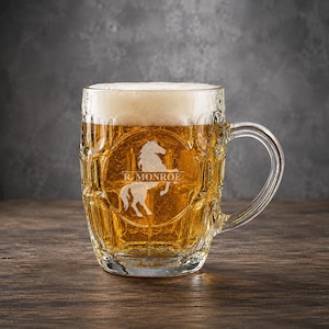 May include: A clear glass beer mug with a dimpled exterior, filled with golden beer and a thick white foam head. The front of the mug features an etched design of a rearing horse silhouette above the text R. MONROE in a clean, sans-serif font.