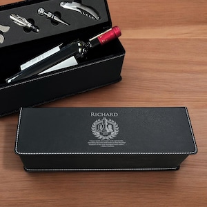 May include: A black leather wine box with a personalized inscription that reads "Richard" and features a chess piece design. The box includes a bottle of wine and a set of wine accessories.