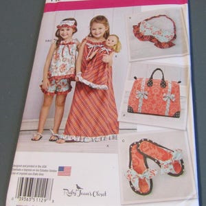 May include: Simplicity sewing pattern 1129 A for children's sleepwear, including a floral top and shorts, a plaid nightgown, a matching doll dress, a ruffled sleep mask, a patterned travel bag, and fabric slippers with bows, sized U.S. 3-8.