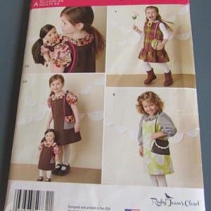 May include: Simplicity sewing pattern S0732 for girls' dresses. The pattern features multiple dress styles, including a plaid dress and a brown dress with a floral collar. The pattern includes sizes 3-8 and is designed and printed in the USA.
