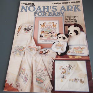 May include: A craft leaflet titled "Noah's Ark for Baby" by Leisure Arts, featuring cross-stitch designs. The cover displays a framed cross-stitch of animals, a panda bear, and embroidered baby items. The leaflet includes 19 designs by Linda Gillum.
