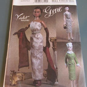 May include: Vogue Doll Collection pattern for a Gene doll, featuring Violet Waters. The pattern includes three different outfits: a long white gown with a red shawl, a black and white patterned dress, and a green plaid suit with a white hat.