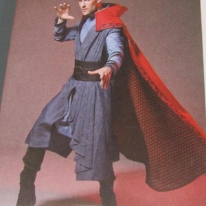 May include: A person wearing a Doctor Strange costume. The costume includes a blue tunic, a red cape with a patterned lining, a black belt, and black boots. The person is posing with their hands in a gesture.