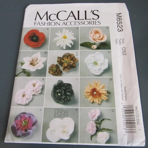 May include: A McCall's M6523 fashion accessories sewing pattern envelope featuring illustrations of various fabric flowers labeled A through M. The white paper envelope includes the text McCall's Fashion Accessories, M6523, and a barcode.