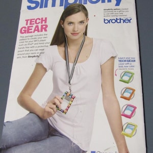 May include: Magazine cover featuring a woman wearing a white shirt and blue jeans, holding a tech gear pouch. The cover promotes a Simplicity pattern for creating MP3 player covers. Text includes "TECH GEAR" and "Simplicity".