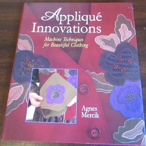 May include: A book titled "Appliqué Innovations: Machine Techniques for Beautiful Clothing" by Agnes Mercik. The cover features a red fabric with colorful appliqués of flowers.