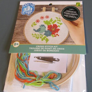 May include: A cross stitch kit with a colorful bird and flower design. The kit includes everything needed to complete the project, including embroidery floss, a needle, and a hoop.