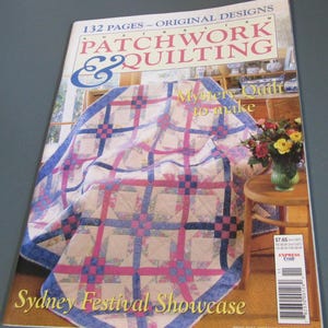 May include: A magazine titled Australian Patchwork & Quilting, Vol. 7 No. 11, featuring 132 pages of original designs. The cover displays a quilt with pink, blue, and cream geometric patterns, a wooden stool with a flower vase, and text.