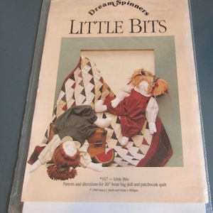 May include: A package featuring the text "Dream Spinners LITTLE BITS" with illustrations of two bean bag dolls and a patchwork quilt. The dolls are wearing red and green outfits. The package includes pattern and directions for a 20-inch bean bag doll and patchwork quilt.