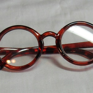 May include: A pair of round, brown-framed glasses with clear lenses.