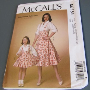 May include: McCall's sewing pattern M7184 featuring a mother and daughter wearing matching dresses. The dresses have a red and white circular pattern. The pattern envelope includes the text "The Archive Collection Circa 1958".